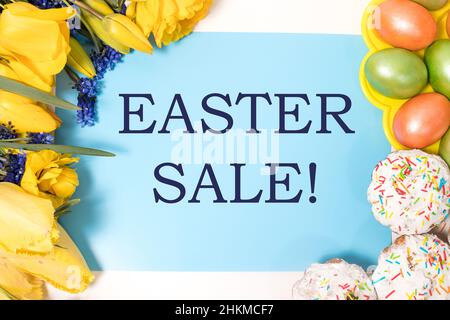Layout with the text Easter sale on a blue background with flowers and painted eggs Stock Photo