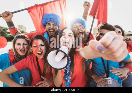 Football fans watching soccer match event at stadium - Young people having fun supporting favorite club - Sport entertainment concept Stock Photo