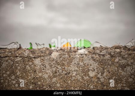 Wall top covered with colorful broken glass. Sharp pieces inlaid on mortar Stock Photo