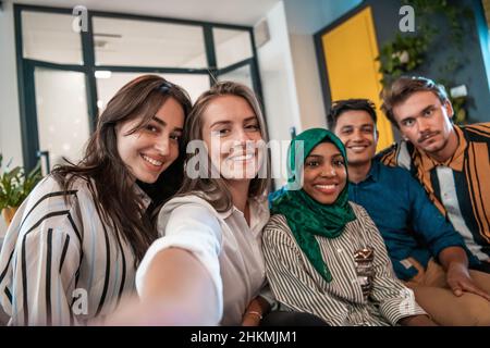 Group of business people during break from the work taking selfie picture while enjoying free time in relaxation area at modern open plan startup Stock Photo