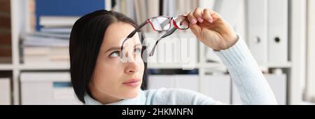 Tired young woman at workplace took off glasses closeup Stock Photo