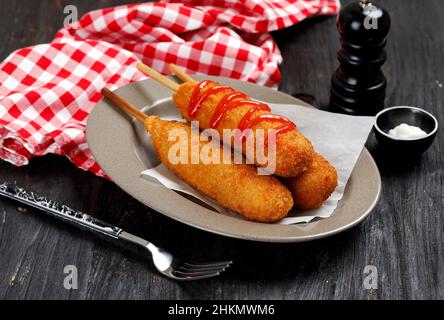 Tasty Corn Dog in A Plate, Served with Ketchup and Mayonaise. On Wooden Table Stock Photo