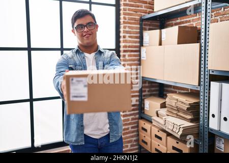 Down syndrome man ecommerce business worker holding package at office Stock Photo