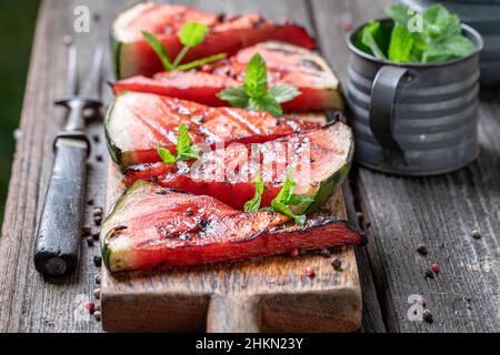 Sweet burned watermelon on grill grate with fire. Roasted watermelon on ...