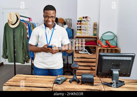 Young african man working as shop assistance using smartphone at retail shop Stock Photo
