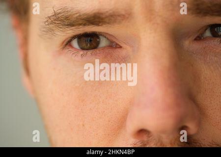Macro shot of brown eyed handsome blonde man, close up of handsome man's part of face and eye. Stock Photo