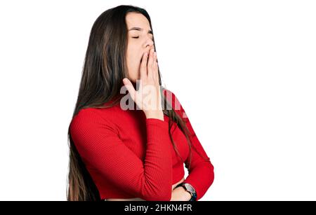 Young brunette teenager wearing red turtleneck sweater bored yawning tired covering mouth with hand. restless and sleepiness. Stock Photo