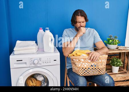 Handsome middle age man waiting for laundry feeling unwell and coughing as symptom for cold or bronchitis. health care concept. Stock Photo