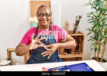 Senior african american woman communicating with deaf language at art studio Stock Photo