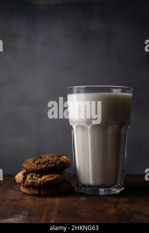 A glass of milk with chocolate chips cookies on a rustic table Stock Photo