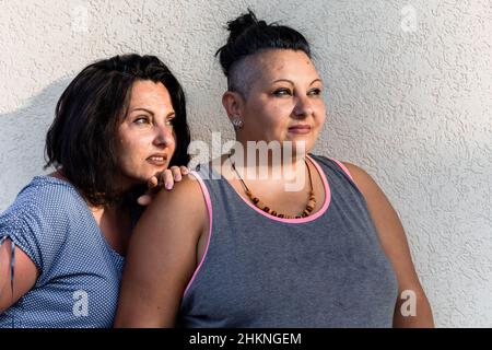 Portrait of two adult brunette twin sisters looking at something. Different styles Stock Photo