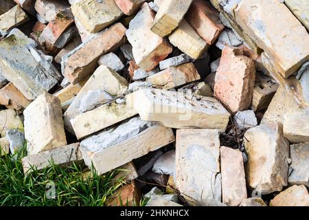 A pile of old used bricks with scratches and cracks from the old wall near the plot. Stock Photo