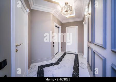 Entrance corridor in a new apartment with a fresh renovation in a minimalist style. Beige-brown tones, marble floors. Stock Photo