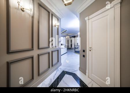 Entrance corridor in a new apartment with a fresh renovation in a minimalist style. Beige-brown tones, marble floors. Stock Photo