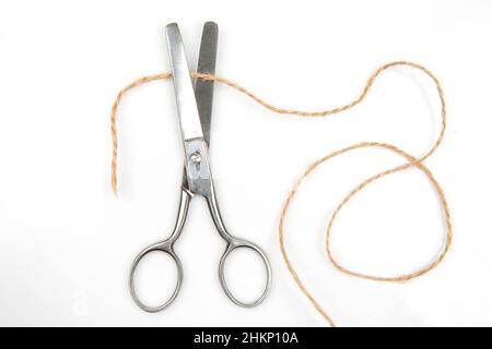 Cutting A Rope With Scissors Against White Background Stock Photo