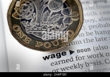 DICTIONARY DEFINITION OF WORD WAGE WITH ONE POUND COIN RE INCOMES COST OF LIVING WAGES SALARY WORKERS PAY ETC UK Stock Photo