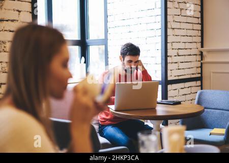 Pensive freelancer working on laptop in cafe Stock Photo