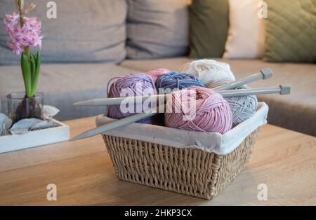 colorful woolen balls in a wooden basket with big knitting needles handmade Stock Photo