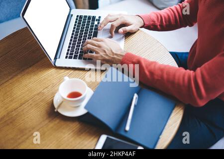 Freelancer typing on laptop in cafe in daytime Stock Photo