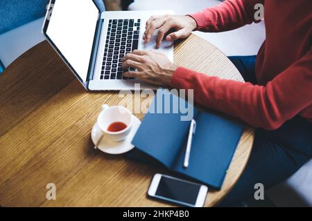 Crop freelancer working on laptop in cafe Stock Photo