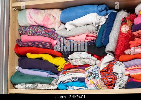 Children's clothes drawer detail, closeup, detail, lots of children's clothes stored in the closet, wardrobe, nobody. Folded clothing piles, unused cl Stock Photo