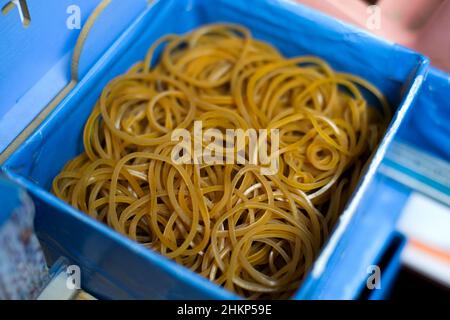 Pile of yellow rubber bands in a blue container Stock Photo