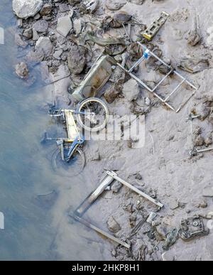 Low tide revealing a selection of items thrown into the muddy River Avon in Bristol UK including Bristol bike street name bollard and scooter Stock Photo