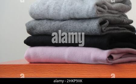 Folded sweaters from dark to light colour made of wool and cashmere. Cosy knitted sweater stack for autumn weather Stock Photo