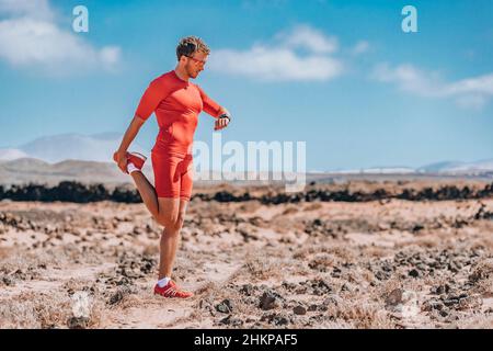 Runner stretching legs using smartwatch for trail run. Athlete checking smart sports watch during endurance Ultra running race training. man doing Stock Photo