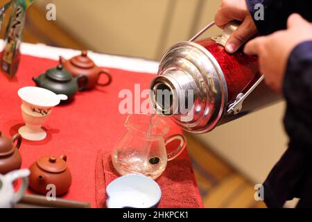Man pours water into glass jug from thermos at the Tea Ceremony Stock Photo