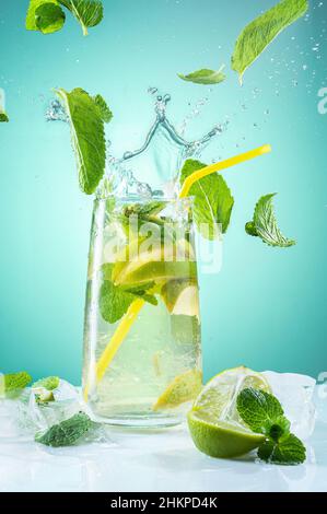 Beautiful and bright photo of a cocktail. Beverage with flying mint leaves. Cocktail splash crown. Summer beverage. Vertical cocktail. Stock Photo