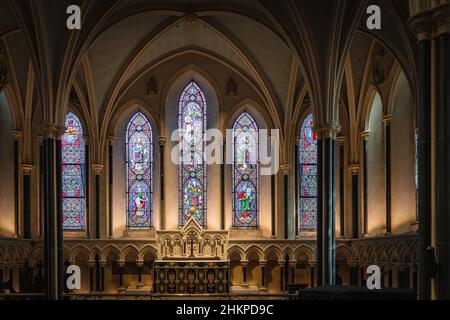 Dublin, Ireland, August 2019 Beautifully illuminated side altar in St. Patricks Cathedral with gothic arches and stained glass Stock Photo