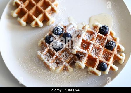 Belgian waffles with fresh fruit and honey on a plate isolated on white background. Directly above. Stock Photo