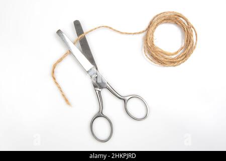 Cutting A Rope With Scissors Against White Background Stock Photo