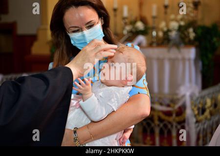 The pastor baptizes a child in the church using holy water Stock Photo