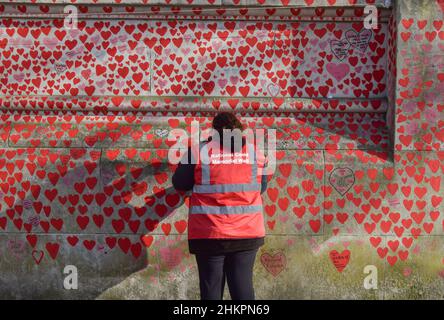 London, UK 4th February 2022. Volunteers paint new hearts and repaint some which have faded over time on the National Covid Memorial Wall. Over 150,000 red hearts have been painted on the wall outside St Thomas' Hospital opposite the Houses of Parliament, one for each life lost to COVID-19 in the UK.