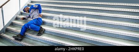 Worker Man Lying On Staircase After Slip And Fall Accident Stock Photo