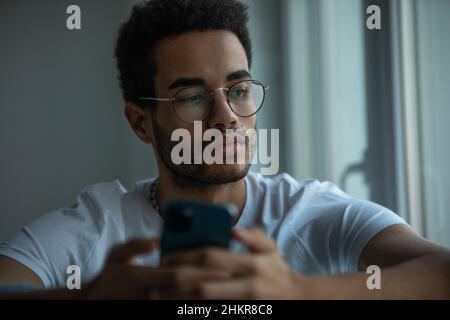 Portrait of an african american man in glasses using a smartphone. Stock Photo