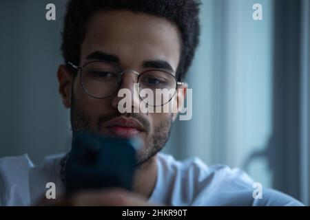 Portrait of an african american man in glasses using a smartphone. Stock Photo