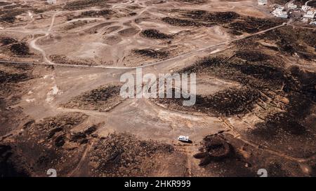 Aerial view of camper van parked in the ground desert alone with offroad roads around. Concept of freedom and vanlife independent travel lifestyle. Al Stock Photo