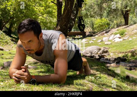 Fit young man exercising in park. latin man doing core workout on grass. Stock Photo