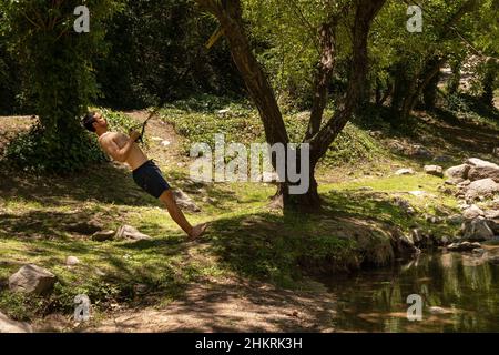 Latin Fit young man is training outdoor on TRX. Copy space Stock Photo