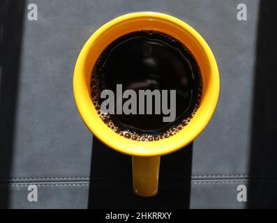 A Bright Yellow Mug Filled with Black Coffee Stock Photo
