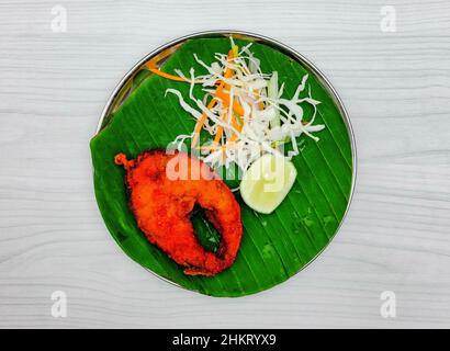 Thai fried fish with lemon on banana leaf top view on grey background Stock Photo