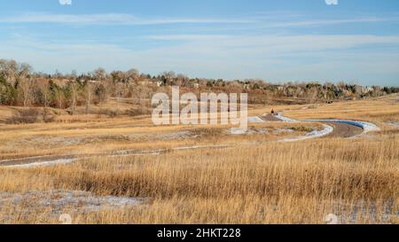 meandering biking trail in Fort Collins, Colorado with distant people walking at warm calm winter afternoon, Cathy Fromme Prairie Natural Area Stock Photo