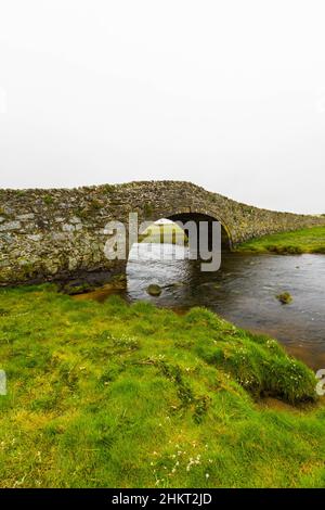 Old hump-backed bridge Pont Pont Aberffraw on Anglesey, Wales UK, wide angle, portrait Stock Photo