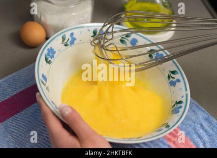 beating hen's eggs in a white bowl with a whisk Stock Photo