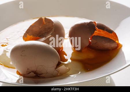 Cracked eggs on white plate with morning light. Brocken eggshell  Stock Photo