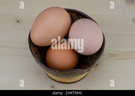 Cooking eggs in a coconut bowl. Protein ingredient for a healthy breakfast. Omelet preparation. Broken eggshells on the table. The transparent, yellow Stock Photo