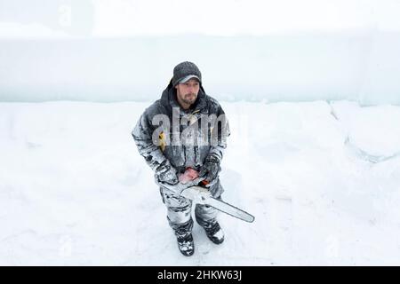 Worker with a chainsaw in hand at the assembly site Stock Photo